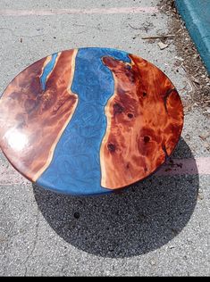 a wooden surfboard sitting on the ground next to a blue and orange stripe line