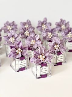 purple flowers are placed in small glass cubes with pearls on the top and bottom