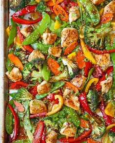 a sheet pan filled with chicken, peppers and broccoli covered in sesame seeds