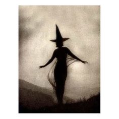 a black and white photo of a woman wearing a witches hat with her arms outstretched