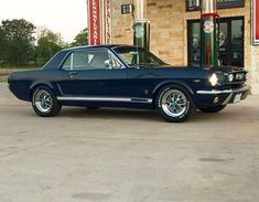 a black mustang parked in front of a gas station