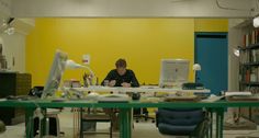 a woman sitting at a table in front of a laptop computer on top of a green table