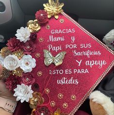 a graduation cap with flowers and butterflies on the front is being held in someone's hand