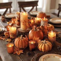 a table topped with candles and pumpkins on top of a wooden dining room table