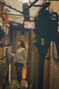 a woman walking down a hallway next to a book shelf