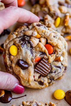 a hand holding a chocolate chip cookie with candy and m & m on the top