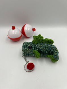 a crocheted broccoli keychain is shown next to two red and white balls