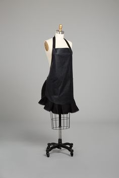 an apron on a mannequin with a black dress underneath it and a white top