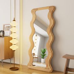 a mirror sitting on top of a wooden floor next to a chair and table with a potted plant