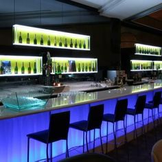 an empty bar with several bottles on the wall and chairs at the counter in front of it