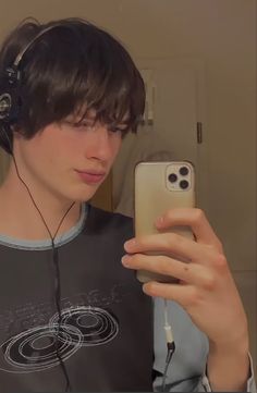 a young man wearing headphones looking at his cell phone