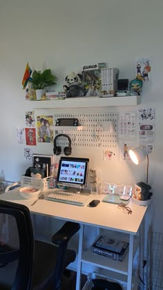 a white desk topped with a laptop computer next to a chair and wall mounted shelves