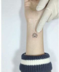 a woman's wrist with a small lotus tattoo on the left side of her arm