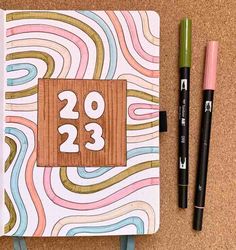 an open notebook with the number twenty two on it next to some markers and pens