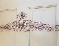 a metal wall hanging on the side of a white door with swirls and scrolls