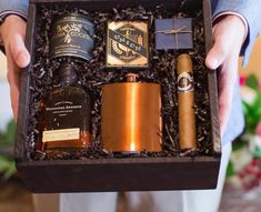 a man holding a box filled with different types of liquor and cigars in it