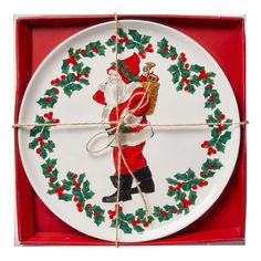 a plate with a santa clause on it in a red box and tied up to the edge