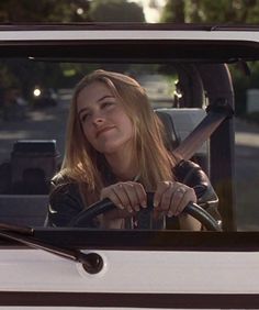 a woman sitting in the driver's seat of a white truck with her hand on the steering wheel