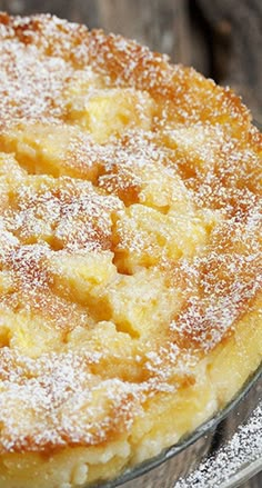 a cake with powdered sugar on top is sitting on a glass platter, ready to be eaten