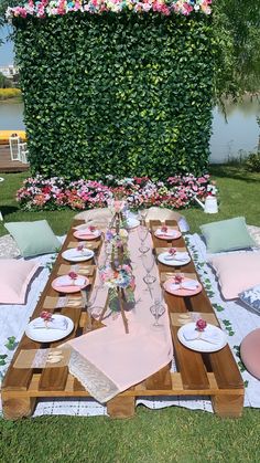 a table set up with plates and place settings for an outdoor dinner on the grass