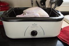 a white and black crock pot sitting on top of a counter next to utensils