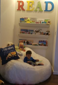 a little boy reading a book in a bean bag chair