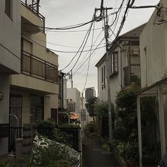 an alley way with power lines above it and buildings on both sides, in the background