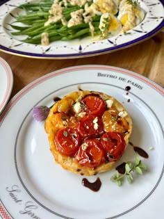 two plates with food on them, one has green beans and the other has tomatoes