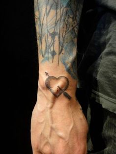 a person with a tattoo on their arm holding a heart shaped object in his hand