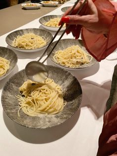 a person is spooning some noodles into bowls