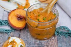 there is a jar filled with food next to two peaches and a cookie on the table