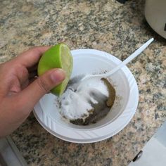 a person holding an apple and spoon in a bowl with powdered sugar on it