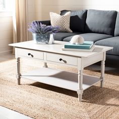 a living room with a couch, coffee table and rug on the floor in front of it