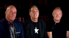 three men standing next to each other in front of a black background with one man wearing a star on his shirt