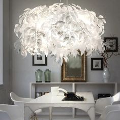 a chandelier hanging over a white table in a room with pictures on the wall