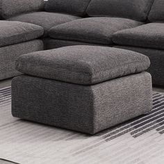 a large gray couch sitting on top of a rug next to a footstool