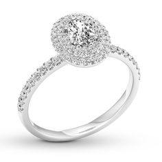 a white gold ring with an oval shaped diamond and pave set diamonds around the band