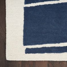 a blue and white rug on top of a wooden floor next to a black cat