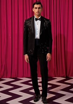 Step into elegance with our Black Textured Tuxedo Set. Crafted from luxurious textured suiting, this set features an elegant black blazer embellished with intricate linear embroidery. Paired with an embellished bowtie, sash, pintuck shirt, and pants, it's the ideal choice for cocktails or wedding receptions. Make a statement and exude sophistication in this stunning tuxedo set. Components : 5 (Blazer, Shirt, Bowtie, Sash and Pants) Composition : Textured Suiting Care: Dry Clean Only and Vacuum Storage This product can be customized for sleeves, length of blouse and neckline Delivery : 4-6 weeks as the product is hand crafted. Check Size Guide or choose MySize for free customisation (All Sizes above XL can be made at 15% additional cost) For more information and sizes please contact fabilic Elegant Evening Sets For Party Season, Sequin Sets For Gala Festive Season, Glamorous Tailored Wedding Suits, Glamorous Formal Sets For Party Season, Glamorous Formal Sets With Sequins, Glamorous Formal Party Sets, Glamorous Formal Sequined Sets, Elegant Long Sleeve Sets For Party Season, Glamorous Sequined Sets For Formal Occasions