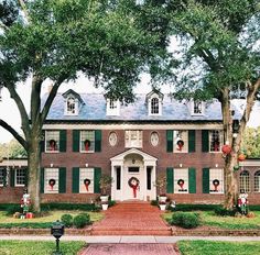 a large red brick house with green shutters and wreaths on the front door