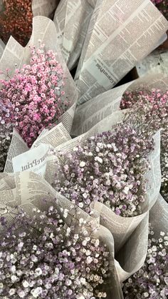 purple and white flowers are wrapped in newspaper