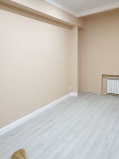 an empty room with a radiator in the corner and a broom on the floor