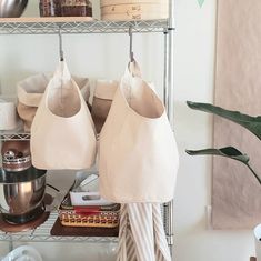 two white purses hanging on a rack in a room with other items and accessories