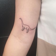 a small black and white cat tattoo on the left inner arm or forearm, with one line running through it