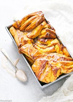 a pan filled with cinnamon rolls next to a spoon