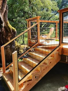 a wooden deck with metal railing next to a tree