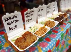 three trays of food are sitting on a table with colorful cloth covered tablescloth