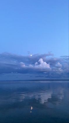 the sky and clouds are reflected in the still water on this calm day at sea