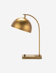 a gold lamp on a white surface with the light turned off and it's arm extended