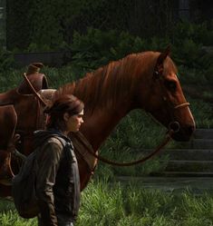 a woman with a backpack walking next to a brown horse in the grass and bushes